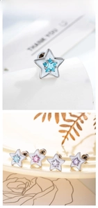 Macro detail of star-shaped zircon earrings with colorful enamel and screw-back safety
