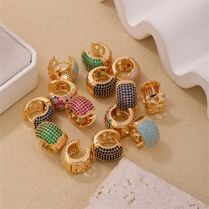 Détail de boucles d'oreilles créoles dorées ornées de zircons multicolores sertis main