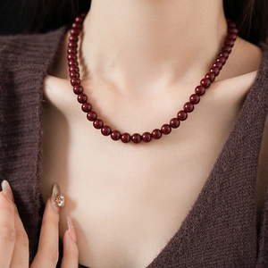 Close-up of red beaded titanium steel necklace worn elegantly by a professional model