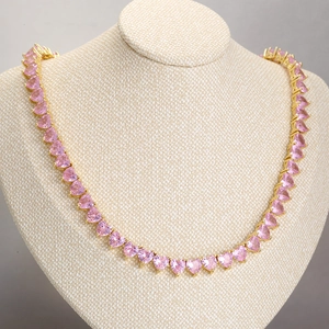 Detailed view of pink heart crystal necklace on a beige display stand showing zircon craft