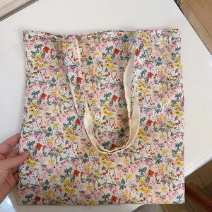 Detail of floral canvas tote bag with dense red and yellow patterns and sturdy shoulder straps