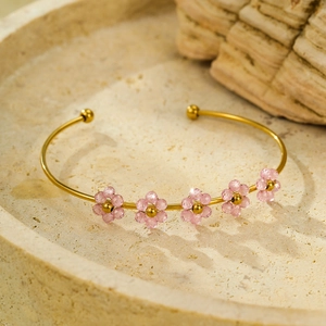 Elegante bracciale in titanio dorato con cinque fiori di cristallo rosa su base