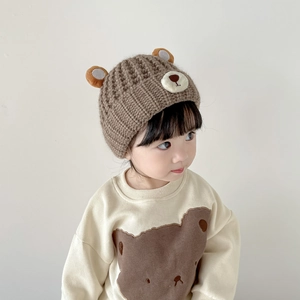 Detail of brown knit baby beanie with bear ears and matching bear print sweatshirt