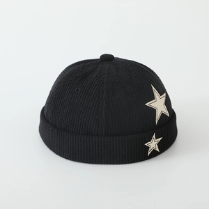Detailed close-up of a black corduroy skullcap with white star patches for boys