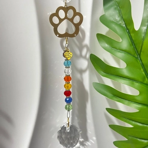 Detail of golden paw suncatcher with rainbow crystal beads and heart-shaped pendant