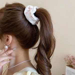 Détail d'un chouchou à fleurs porté par un mannequin avec bijoux en perles raffinés