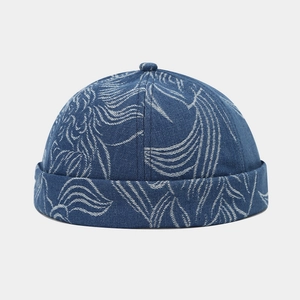 Detail of embroidered leaf patterns on blue denim docker hat with folded brim