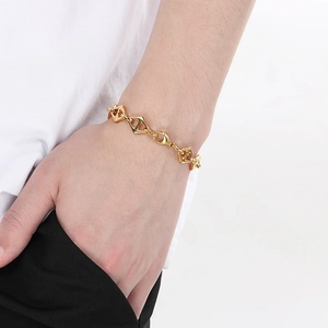 Close-up of polished gold-finished geometric diamond link bracelet worn on a wrist