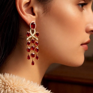 Macro view of vintage gold tassel earrings with red ruby-style gemstones on model