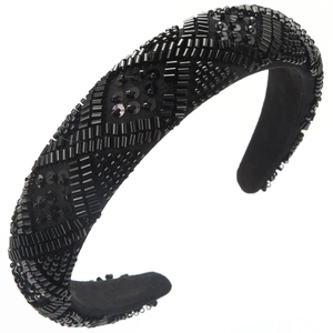 Detail of handmade beadwork with geometric diamond patterns on a black wide headband