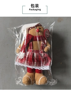 Detailed view of plush gingerbread man toy in packaging with Christmas scarf and hat
