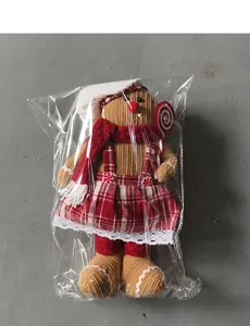 Detailed view of plush gingerbread man toy in packaging with Christmas scarf and hat
