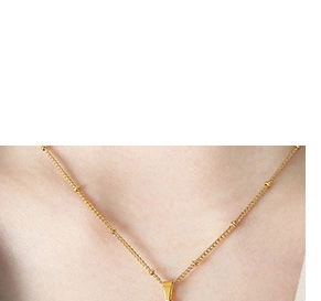 Detail shot of a gold bead chain necklace with pendant clasp on model's neckline