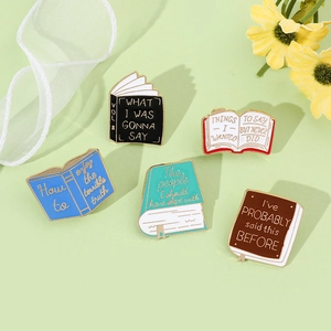 Detailed flat lay of five colorful enamel book pins with creative titles and lettering