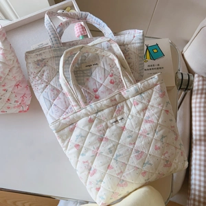 Close-up of quilted floral cotton tote bags with simple wish label on white tray