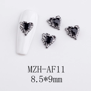Macro detail of gothic silver heart nail charm with black gem and wing carving