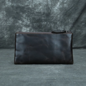 Close-up of a vintage dark brown leather long wallet with a smooth metal zipper detail
