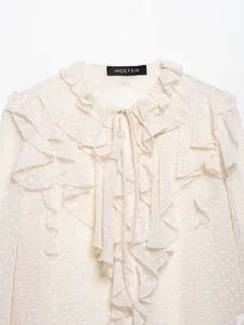 Details der cremeweißen Chiffonbluse mit Tupfenmuster, Rüschenkragen und Schnürung