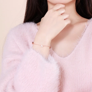 Elegant rose gold triangle bracelet with pavé diamonds on model wrist with soft pink mood