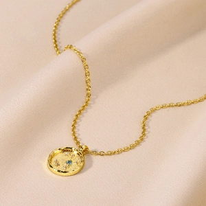 Close-up of gold star sign pendant with blue and white stones on silk fabric