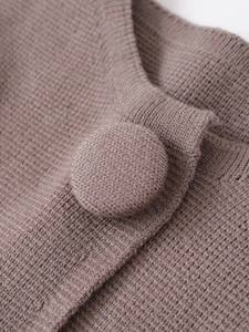 Détail de la maille gaufrée et du bouton recouvert d'un cardigan en maille marron