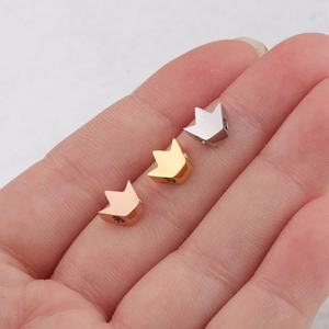 Détail de trois breloques en forme de couronne en or rose, or et argent brillant