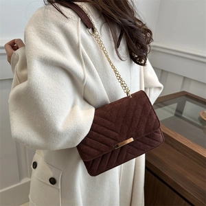 Dark brown quilted chevron suede crossbody bag with gold chain strap worn by a model