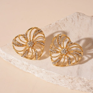 Elegant gold hollow heart earrings with rhinestones on a white marble pedestal