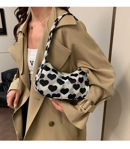 Sac sous le bras tendance à imprimé cœur gris porté avec un trench-coat beige