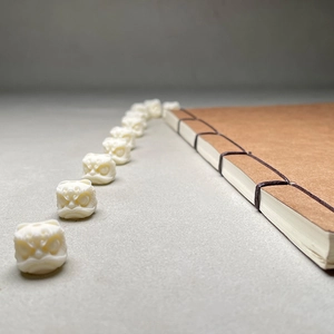 Handcrafted ivory-like lion head beads for jewelry making on vintage book background