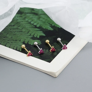 Detailed macro view of S925 silver clover earrings with red stones on a book page