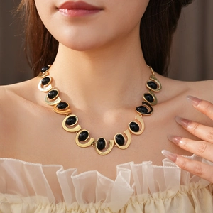 Détail d'un collier doré avec pierres précieuses ovales noires sur maillons en U
