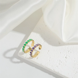 Detailed shot of adjustable gold rings with green and purple enamel hearts on stone