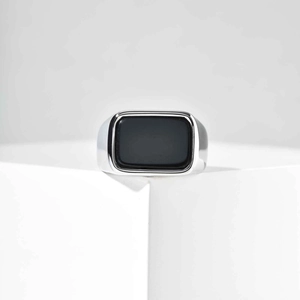 Detailed close-up of a silver signet ring featuring a rectangular black stone on a white pedestal