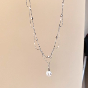 Détail d'un collier double épaisseur en argent avec perles polies et perle blanche