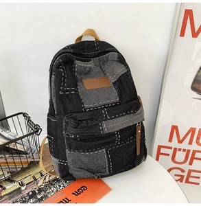 Detailed close-up of retro denim backpack with white stitching and leather brand patch