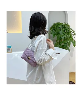 Detailed view of purple quilted shoulder bag with gold chain and diamond clasp on model