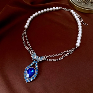Detailed macro view of a blue teardrop gemstone pendant with a sparkling crystal bow