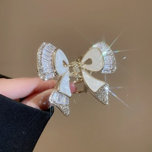 Dettaglio macro della raffinata pinza per capelli a farfalla con zirconi e ali in smalto bianco