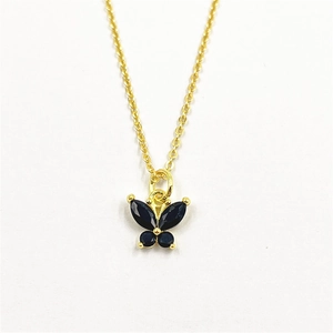 Gros plan d'un pendentif papillon doré avec zircons noirs sertis pour femme élégante