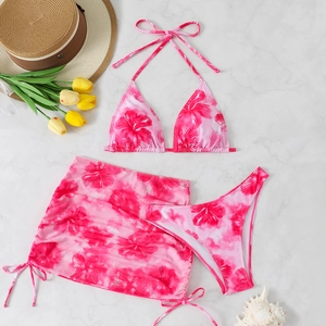 Three-piece women's floral bikini set with halter top and drawstring skirt on marble