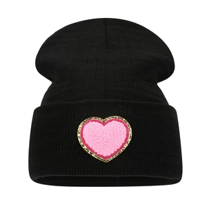 Women's black knit beanie with pink heart patch and gold glitter edges for winter warmth