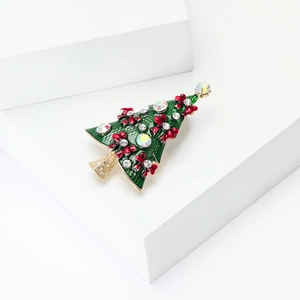 Grüne Emaille Weihnachtsbaum Brosche mit roten Schleifen und Kristallen auf weißem Podest