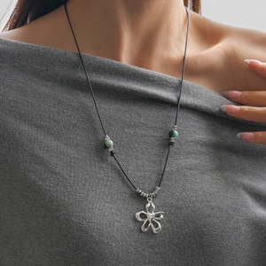 Détail du collier en cordon de cire avec perles en céramique et pendentif fleur