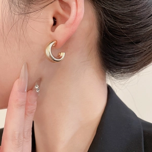 Detailed view of gold C-shaped hoop earrings with textured horizontal ribbing finish