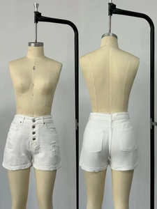 Detail of white high-waist denim shorts featuring a four-button fly and distressed finish