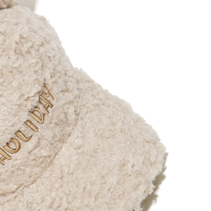 Macro detail of beige fleece baseball cap featuring gold HOLIDAY letter embroidery