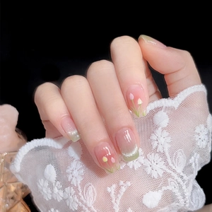 Detail of nude pink press-on nails with green gradient French tips and tulip pattern
