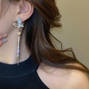 Détail de boucles d'oreilles papillon asymétriques avec de longues franges sur un modèle