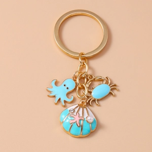 Detail of blue enamel octopus, crab, and shell charms with a pearl on a gold keychain
